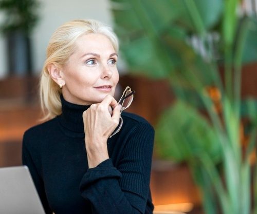 older-woman-holding-glasses-working-laptop_23-2148661215